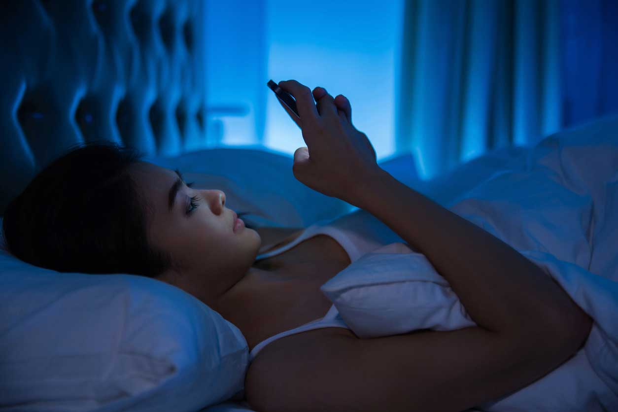 Woman in bed with phone at night