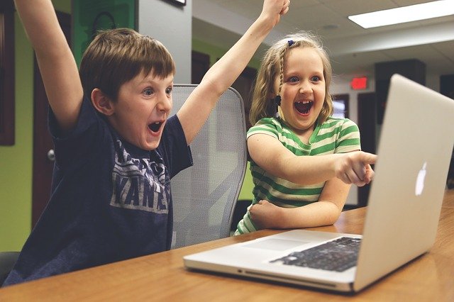 Two children cheering with their laptop