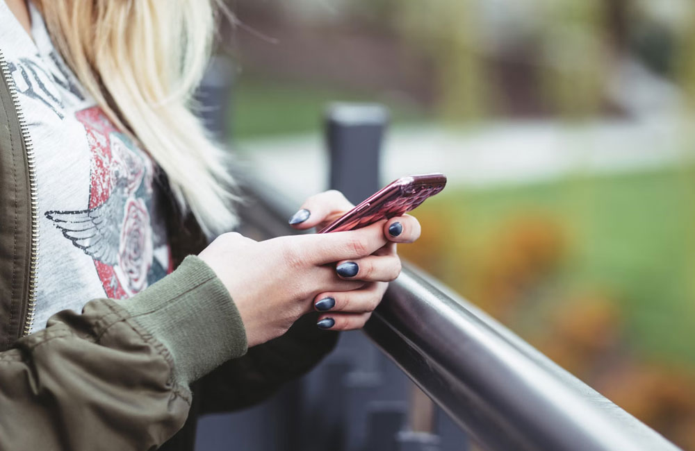 Woman's hands with black painted nails, holding a phone